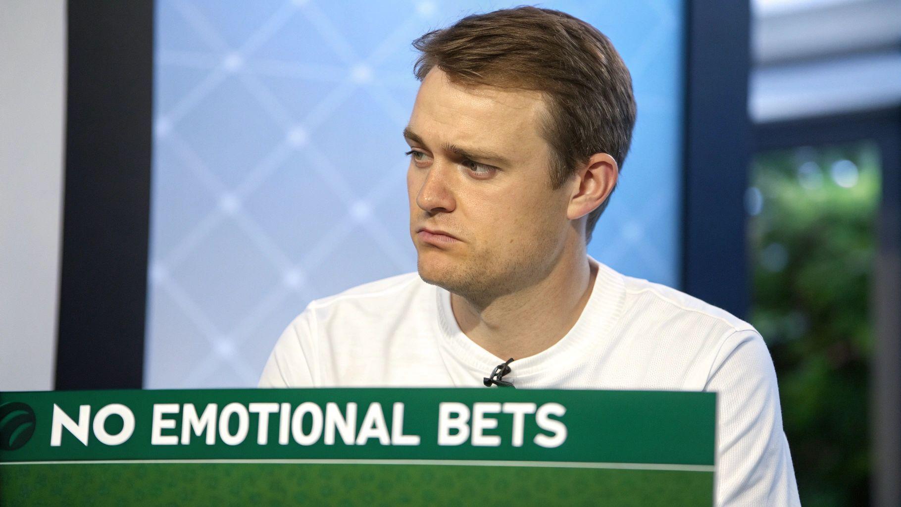 A person looking frustrated while watching a sports game on a screen with betting odds.